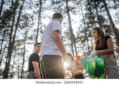 group of teenage friends gen Z male and female caucasian men women picking up waste garbage plastic bottles and paper from the forest cleaning up nature in sunny day environmental care ecology concept - Powered by Shutterstock