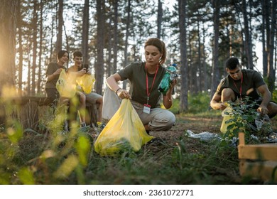 group of teenage friends gen Z male and female caucasian men women picking up waste garbage plastic bottles and paper from the forest cleaning up nature in sunny day environmental care ecology concept - Powered by Shutterstock