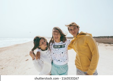 Group of teenage friends having fun on the beach. Hipster boy and girls playing outdoors.