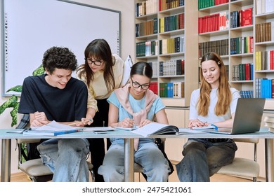 Group of teenage students with female teacher study inside classroom library - Powered by Shutterstock