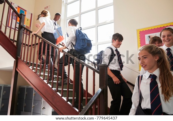 Group Of Teenage Students In Uniform Walking\
Between Classrooms