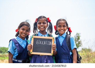 group of teenage Village girl kids in school uniform holding slate with education writings looking at camera - concept of development, education and girl kid development