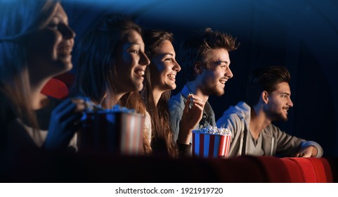 Group of teenager friends at the cinema watching a movie together and eating popcorn, entertainment and enjoyment concept - Powered by Shutterstock