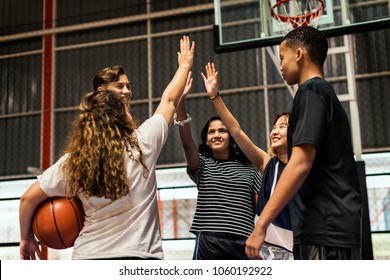 Group of teenager friends on a basketball court giving each other a high five - Powered by Shutterstock