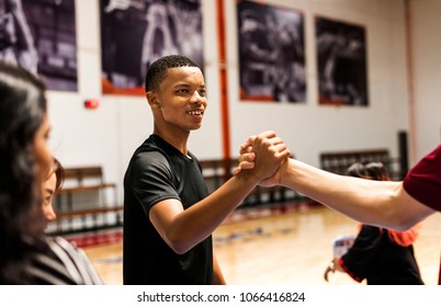 Group of teenager friends on a basketball court giving each other a high five - Powered by Shutterstock