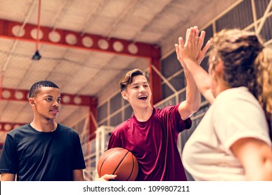 Group of teenager friends on a basketball court giving each other a high five