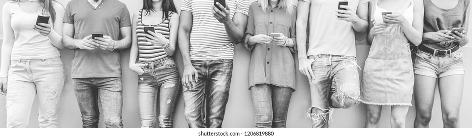 Group of teenager friends watching smart mobile phones - Millennial generation using new technology trends - Concept of youth, tech and social network - Focus on center hands - Black and white editing - Shutterstock ID 1206819880
