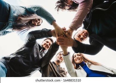 Group of teenagers of different cultures at the park - Teamwork of young people forming a circle - Six men and women having fun together - Bottom view of people putting their hands