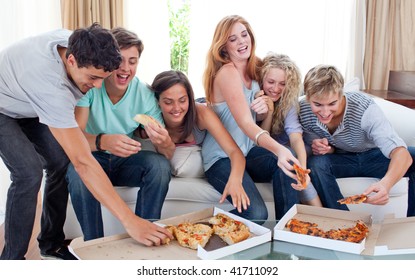 Group Of Teenagers Eating Pizza In The Living-room On The Sofa