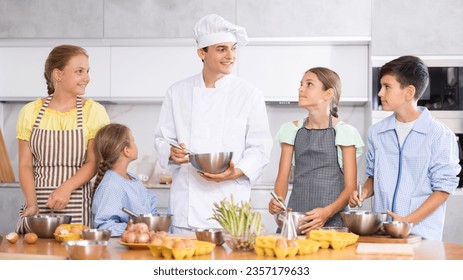 Group of teenagers and friendly chef cook cooking in kitchen. Learn to beat raw eggs - Powered by Shutterstock