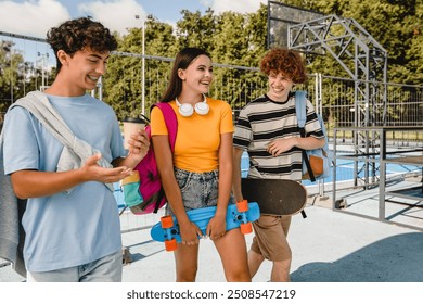 Group of teenagers high school pupils classmates college students friends boys and girls with skateboards bags talking walking laughing out hanging out having fun in skate park sport court outside - Powered by Shutterstock