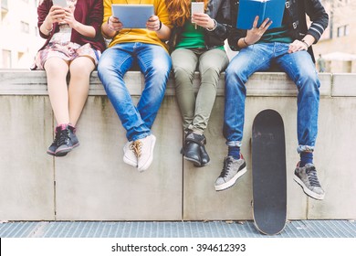 Group of teenagers making different activities sitting in an urban area