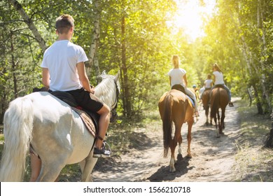 Group Of Teenagers On Horseback Riding In Summer Park, Back View