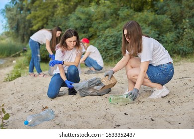 Group of teenagers on riverbank picking up plastic trash in bags. Environmental protection, youth, volunteering, charity, and ecology concept - Powered by Shutterstock