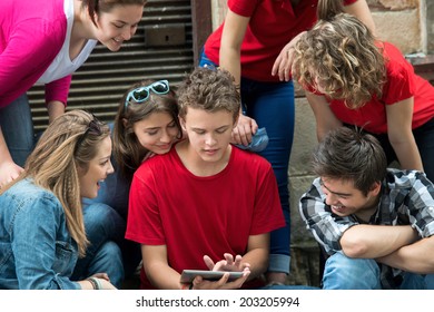 Eine Gruppe von Teenagern, die auf einer Tablette im Freien lesen