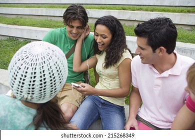 Group Of Teenagers Relaxing, Couple Listening To MP3 Player, Sharing Headphones