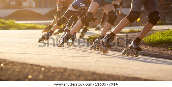 Group of\
teenagers skating on track in summer evening. Abstract panoramic\
short track speed skating sport\
background