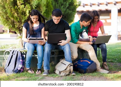 Group Of Teenagers Social Networking Using Several Tech Devices In High School