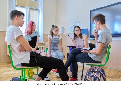 Group Of Teenagers With Young Female Teacher At Classroom, Sitting Talking Discussing. Education, Lesson, Youth, Teaching, School, College Concept