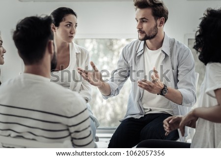 Group therapist. Nice pleasant young man looking at the group members and speaking to them while telling his story