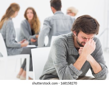 Group Therapy In Session Sitting In A Circle With Therapist While Man In Foreground