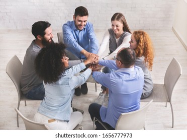 Group Therapy Success. Happy People Sitting In Circle And Stacking Hands, Celebrating Successful Recovery From Addiction