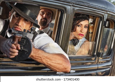 Group of three 1920s era gangsters shooting from car window