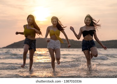 Group Of Three Asian Beautiful Attractive Young Woman Playing And Running On The Beach At The Sea. Group Of Happy Friends Runs To The Sea With Tropical Beach At Sunny Evening. Beach Holidays Concept