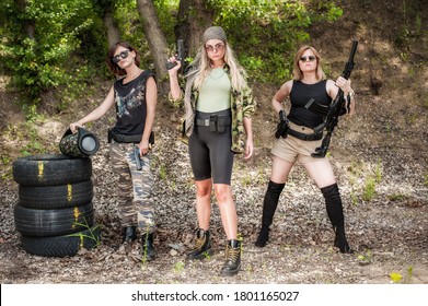 Group of three beautiful and attractive female soldier with guns and rifle machine gun. Woman with weapon. Outdoor shooting range. Fashion model style