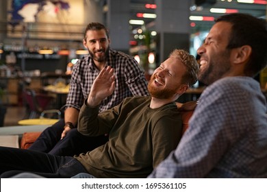 Group Of Three Best Friends Laughing And Enjoying The Evening At Pub. Happy Young Men Enjoying Late Night Staying Together At Bar. Cheerful Guys Sitting On Couch And Having Fun While Relaxing.