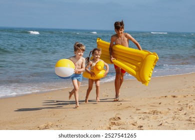 Group of three children, boys and girl, carrying inflatable toys, cheerfully run along the sandy shore with the waves in the background - Powered by Shutterstock