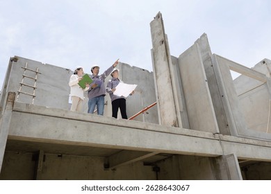A group of three construction workers and inspector review plans together on a building site