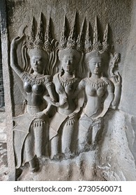 A group of three Devatas, each unique in appearance, but similar ornamental head pieces. Each of the thousand Devatas of Angkor Wat are unique and that makes viewing them a worthwhile experience. Angkor Wat, Angkor Archeological Park, Siem Reap Province, Cambodia.