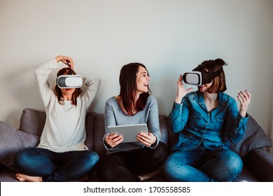 
Group Of Three Friends And Roommates Playing A Virtual Reality Game, Wearing Vr Glasses. Fun And Relaxed During Quarantine Days At Home. Lifestyle