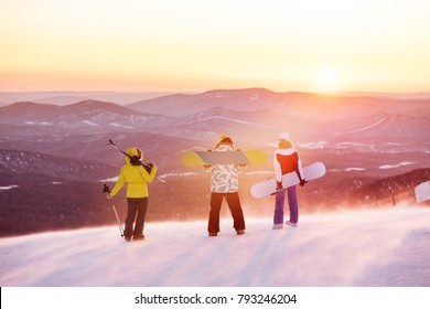 Group Of Three Friends At Ski Resort Against Sunset