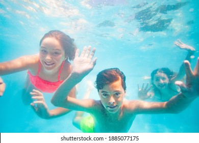 Group of three friends young kids dive underwater together waving hands and smiling