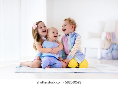 Group of three kids playing in a white bedroom. Children play at home. Preschooler girl, toddler boy and baby in nursery. Happy little brothers and sister bonding having fun together. Siblings love