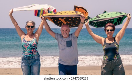 Group of three mature people standing on the beach waving towels in the wind looking into the camera. Relaxed vacation concept - Powered by Shutterstock