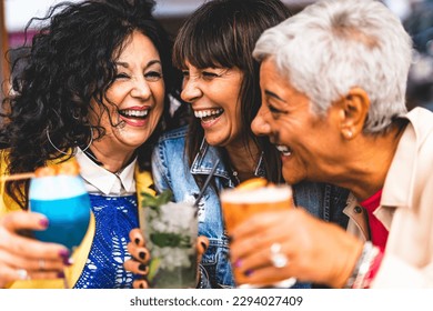 Group of three mature women drinking cocktails outdoors at bar restaurant-Happy senior friends enjoying happy hour holding fancy drink at city pub - Life Style and Fun concept with older female - Powered by Shutterstock