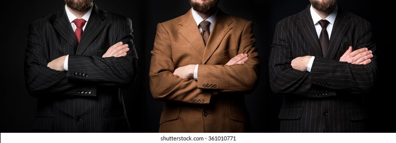 Group Of Three Men In Suits Black Background
