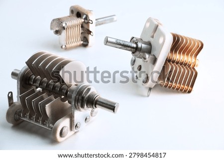 Group of three old electronic component variable capacitors on white background