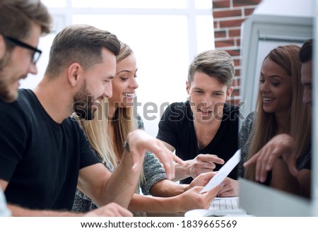 Group of three people analyze data on desktop computer.