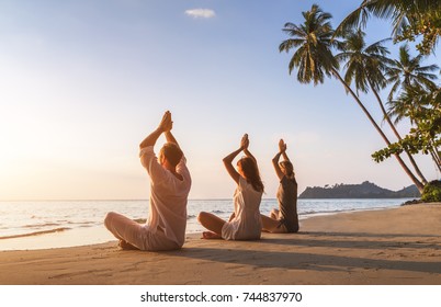 Group of three people practicing yoga lotus position on the beach for relaxation and wellbeing, warm tropical summer landscape with palm trees - Powered by Shutterstock