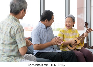 A group of three senior Asian people living together and enjoin playing music, sing a song and clapping hands with happiness. Concept for happy lifestyle of grandparents and older people.