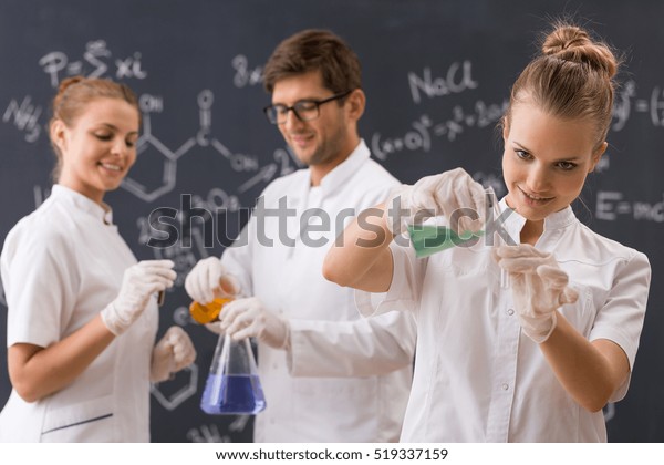 Group Three Students Conducting Experiment Blackboard Stock Photo Group Three Students Conducting Experiment Blackboard Stock Photo