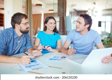 Group Of Three Successful Business Partners In Casual Working At Meeting In Office