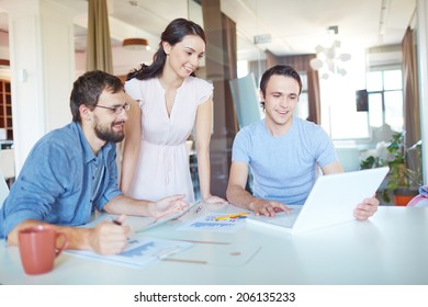 Group Of Three Successful Business Partners In Casual Working At Meeting In Office