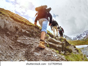 Group of three tourists walking uphill by trek in mountains
