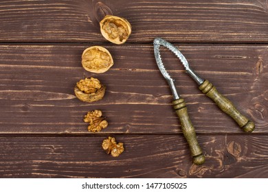 Group Of Three Whole Two Pieces Of Ripe Brown Walnut With Old Nutcracker Flatlay On Brown Wood