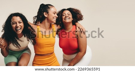 Group of three young, diverse female athletes celebrate their healthy and active lifestyle in a sports studio, smiling and laughing together while wearing sporty fitness clothes. Stock foto © 